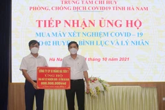 Phó Chủ tịch UBND tỉnh Hà Nam Trần Xuân Dưỡng tiếp nhận ủng hộ của các doanh nghiệp. (Ảnh: Thanh Tuấn/TTXVN)