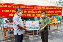 Đại tá Đinh Văn Nơi, Giám đốc Công an tỉnh trao bảng hỗ trợ quà cho lãnh đạo huyện Phú Tân, An Giang. (Ảnh: Thanh Sang/TTXVN)