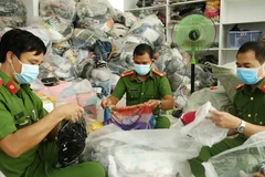 Lực lượng chức năng kiểm đếm các sản phẩm quần áo, túi sách không rõ nguồn gốc, nhập lậu tại cơ sở kinh doanh Trần Lan. (Ảnh: TTXVN phát)