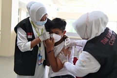 Nhân viên y tế tiêm vaccine phòng COVID-19 cho học sinh tại Banda Aceh, Indonesia, ngày 9/11/2021. (Ảnh: AFP/TTXVN)