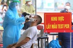 Nhân viên y tế mặc đồ bảo hộ thực hiện xét nghiệm COVID-19 cho người dân tại Hà Nội. (Ảnh: Hoàng Hiếu/TTXVN)