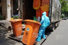 Công nhân vệ sinh thu gom, vận chuyển chất thải tại các cơ sở cách ly COVID-19. (Ảnh: Hồng Giang/TTXVN)