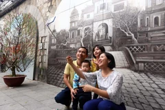 Người dân thủ đô chụp ảnh lưu niệm tại phố Bích họa Phùng Hưng. (Ảnh: Danh Lam/TTXVN)