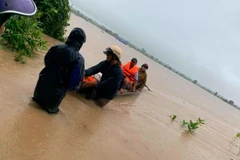 Lực lượng chức năng đưa người dân bị mắc kẹt vào bờ an toàn. (Nguồn: sggp.org.vn)