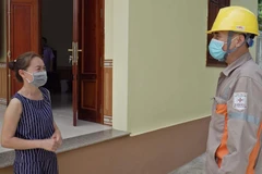 Cán bộ Điện lực huyện Kim Bôi giải thích cho người dân ngành điện không bán loại bảo hiểm tai nạn hộ dùng điện. (Ảnh: Thanh Hải/TTXVN)