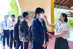 Thí sinh được đo thân nhiệt trước khi vào điểm thi. (Ảnh: Thu Hiền/TTXVN)