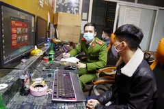 Công an lập biên bản các thanh niên chơi game vi phạm quy định phòng chống dịch COVID-19. (Ảnh: TTXVN phát)