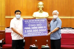 Chủ tịch Ủy ban Trung ương Mặt trận Tổ quốc Việt Nam Đỗ Văn Chiến tiếp nhận ủng hộ Quỹ vaccine phòng COVID-19 từ Bộ trưởng Bộ Kế hoạch và Đầu tư Nguyễn Chí Dũng. (Ảnh: Minh Đức/TTXVN)