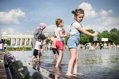 Các em nhỏ tránh nóng bên đài phun nước tại Moskva, Nga. (Ảnh: Getty Images/ TTXVN)