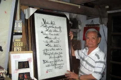 Nghệ sỹ Lê Văn Kinh với các bức tranh thêu của mình. (Ảnh: Quốc Việt/Vietnam+)