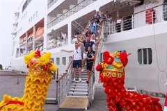 Du khách hào hứng với màn múa lân chào đón khi vừa xuống tàu. (Ảnh: Trần Lê Lâm/TTXVN)