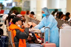 Nhân viên của Cảng hàng không phục vụ suất ăn và nước uống miễn phí đối với những hành khách đang chờ làm thủ tục y tế và đi đến điểm cách ly theo đúng quy định. (Ảnh: CTV/Vietnam+)