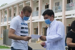 Bác sỹ Trần Chánh Xuân, Phó Giám đốc Bệnh viện Dã chiến Củ Chi trao chứng nhận xuất viện cho bệnh nhân mắc COVID-19. (Ảnh: Đinh Hằng/TTXVN)