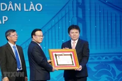 Phó Thủ tướng chính phủ Lào Somdee Duangdee (giữa) trao tặng Huân chương Lao động hạng Nhất cho LaoVietBank. (Ảnh: Xuân Tú/TTXVN)