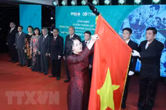 Thừa ủy quyền của Chủ tịch nước, Phó Chủ tịch nước Đặng Thị Ngọc Thịnh gắn danh hiệu Anh hùng Lực lượng vũ trang nhân dân tặng Thông tấn xã Giải phóng lên lá cờ truyền thống của TTXVN. (Ảnh: Lâm Khánh/TTXVN) 
