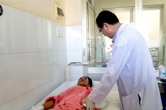 Tiến sỹ, bác sỹ Ngô Đức Hiệp, Trưởng Khoa Phỏng-Phẫu thuật tạo hình khám cho một sản phụ sau sinh bị bỏng do sưởi than. (Ảnh: Đinh Hằng/TTXVN)