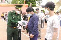 Cán bộ biên phòng trao Giấy chứng nhận hoàn thành cách ly phòng chống dịch bệnh COVID-19 cho các công dân. (Ảnh: Võ Dung/TTXVN)