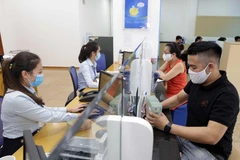 Khách hàng giao dịch tại BaoViet Bank, số 8 Lê Thái Tổ, Hà Nội. (Ảnh: Trần Việt/TTXVN)