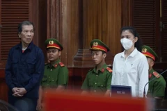 Hai bị cáo Trần Văn Sỹ (trái) và bị cáo Đặng Thị Hàn Ni (phải) đứng nghe tuyên án. (Ảnh: Hồng Giang/TTXVN)