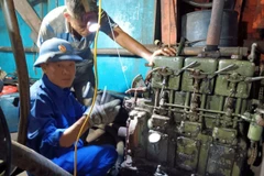 Cán bộ kỹ thuật Âu tàu đảo Sinh Tồn giúp ngư dân sửa chữa máy phát điện của tàu cá QNg 90431 TS. Ảnh: TTXVN phát
