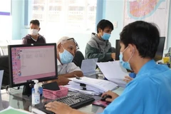 Cán bộ UBND phường Hiệp Bình Chánh, thành phố Thủ Đức, Thành phố Hồ Chí Minh giải quyết hồ sơ cho người dân. (Ảnh: Xuân Tình/TTXVN)