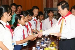 Chủ tịch nước Nguyễn Minh Triết tặng quà cho các cháu. (Ảnh: Nguyễn Khang/TTXVN)