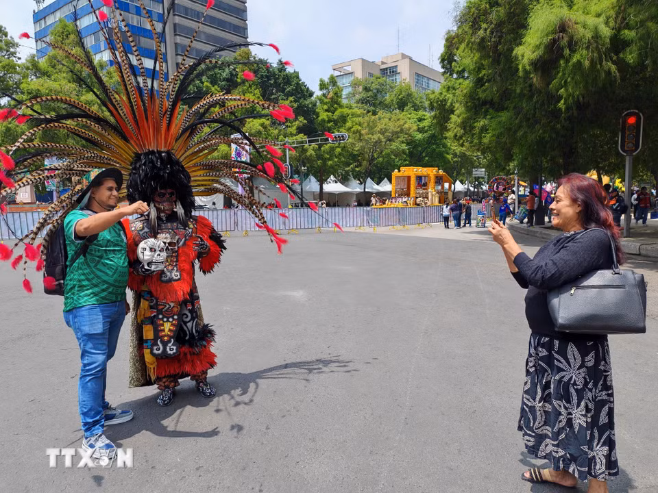 Người dân và du khách lưu giữ những khoảnh khắc đáng nhớ tại lễ diễu hành văn hóa ở Mexico City. (Ảnh: Phương Lan/TTXVN)
