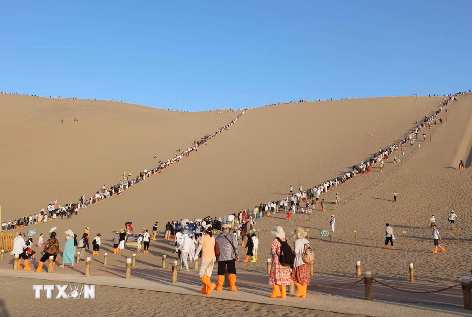 Nhiều du khách lựa chọn leo lên đỉnh cồn cát để ngắm bình minh hoặc hoàng hôn trên sa mạc, trải nghiệm trượt cát. (Ảnh: Công Tuyên/TTXVN)