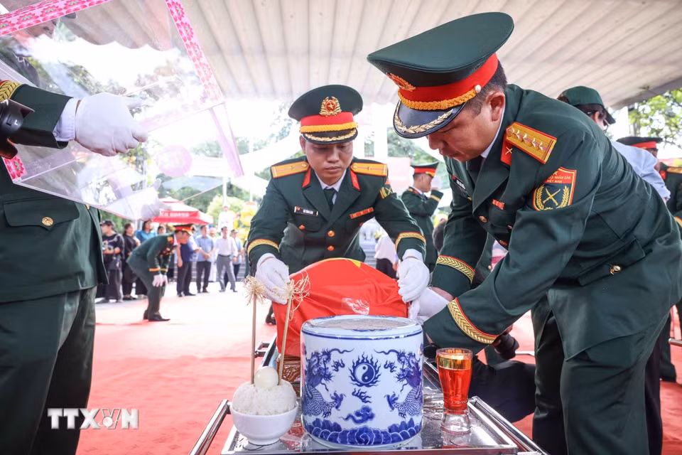 Thành viên Đội tìm kiếm, quy tập hài cốt liệt sỹ tỉnh Hà Giang với hài cốt các liệt sỹ mới được quy tập về Nghĩa trang liệt sỹ Quốc gia Vị Xuyên. (Ảnh: Hoàng Hiếu/TTXVN)