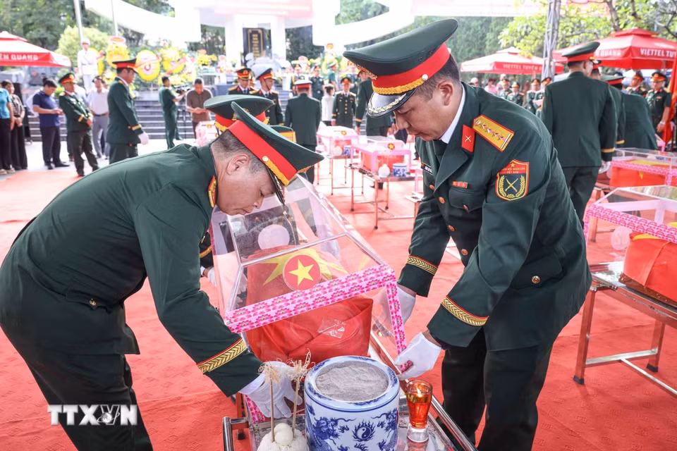 Thành viên Đội tìm kiếm, quy tập hài cốt liệt sỹ tỉnh Hà Giang với hài cốt các liệt sỹ mới được quy tập về Nghĩa trang liệt sỹ Quốc gia Vị Xuyên. (Ảnh: Hoàng Hiếu/TTXVN)