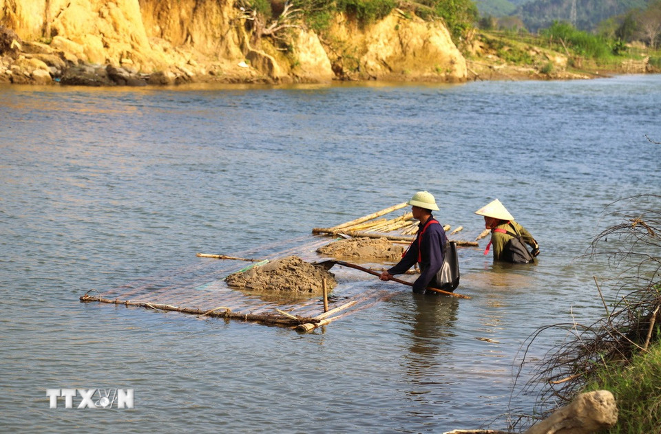 Khai thác cát “chui” theo phương thức thủ công xúc cát lên bè mảng không gây ra tiếng động nên khó bị lực lượng chức năng phát hiện. (Ảnh: Xuân Tiến/TTXVN)