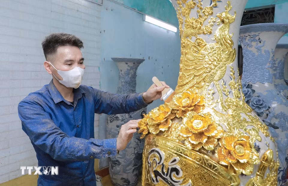 Công đoạn dát vàng thủ công được thực hiện tỉ mỉ, từng lớp vàng kim tạo nên sắc ánh rực rỡ cho sản phẩm. (Ảnh: Phan Phương/TTXVN)