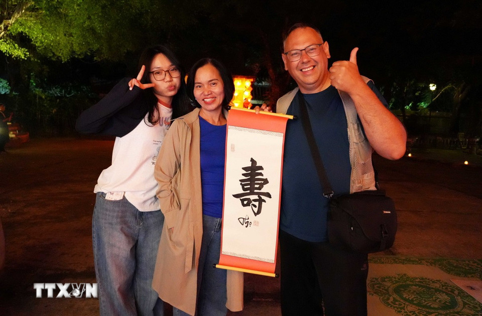 Du khách phấn khởi khi được tặng chữ thư pháp tại chương trình “Tết Hoàng cung” ở Đại Nội Huế. (Ảnh: Nguyên Lý/TTXVN)