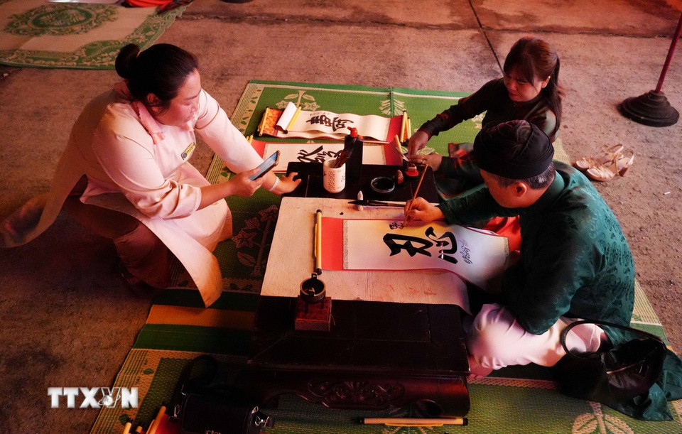 Trình diễn thư pháp tặng chữ tại Chương trình “Tết Hoàng cung” ở Đại Nội Huế. (Ảnh: Nguyên Lý/TTXVN)