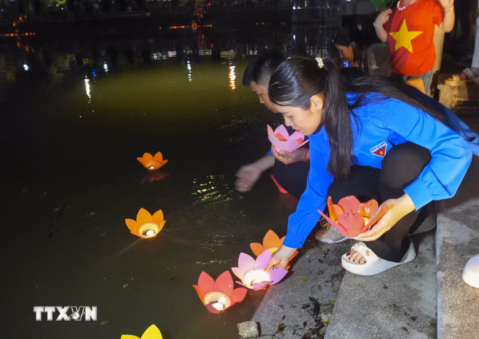 Đoàn viên thanh niên thả hoa đăng xuống sông Nậm Rốm. (Ảnh: Xuân Tư/TTXVN)