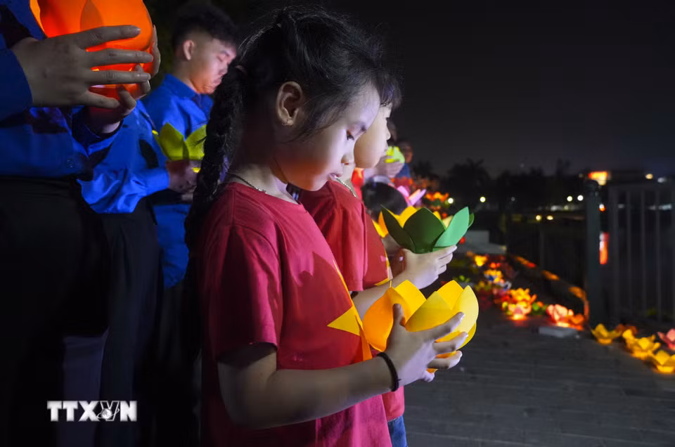Các em nhỏ cũng tham gia hoạt động thả hoa đăng xuống sông Nậm Rốm. (Ảnh: Xuân Tư/TTXVN)