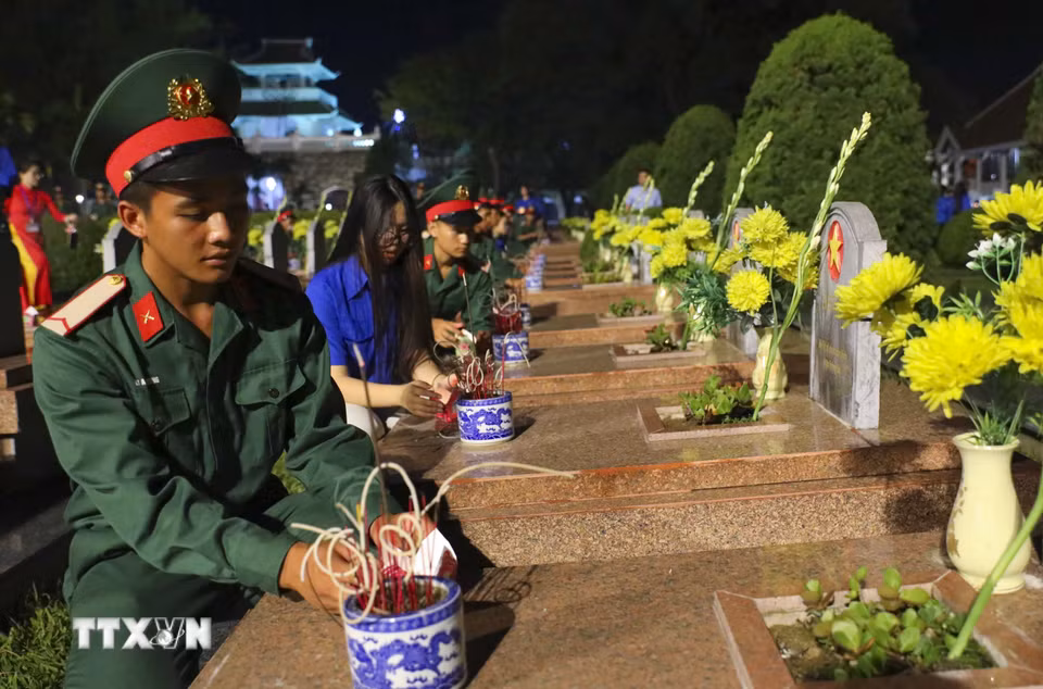 Đoàn viên thanh niên thắp nến tri ân lên các phần mộ liệt sỹ tại Nghĩa trang A1. (Ảnh: Xuân Tư/TTXVN)