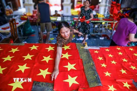 Người thợ kiểm tra lại từng sản phẩm, chỉnh sửa những chi tiết nhỏ nhất để đảm bảo mỗi lá cờ đều đạt chuẩn. (Ảnh: Lê Ngọc/TTXVN phát)
