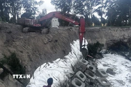 Mỗi khối bê tông đúc sẵn nặng 2,5 tấn được đặt trên lớp vải địa kỹ thuật để “hàn”, những khu vực bờ biển An Bàng bị sóng biển ăn sâu vào đất liền. (Ảnh: Đoàn Hữu Trung/TTXVN)
