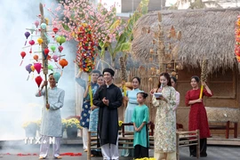 Bạn trẻ mặc áo dài truyền thống chụp ảnh lưu niệm tại không gian Tết xưa. (Ảnh: Đặng Tuấn/TTXVN)