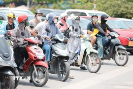 Khẩu trang, áo chống nắng là những thứ không thể thiếu của người dân khi tham gia giao thông. (Ảnh: Lê Đông/TTXVN)