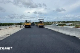 Nhà thầu huy động máy móc thi công thảm nhựa nền đường. (Ảnh: Việt Hùng/Vietnam+)