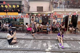 Nhiều du khách nước ngoài tranh thủ "check-in" tại "phố càphê đường tàu" ở Hà Nội, sáng 15/6. (Ảnh: Thành Phương/TTXVN)