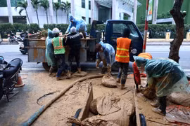 Công nhân Công ty vệ sinh môi trường đô thị Hà Nội tiếp tục dọn dẹp những vật dụng dùng trong lúc xử lý bùn nhão phun trào (ảnh chụp chiều 23/2).( Ảnh: An Đăng/TTXVN)