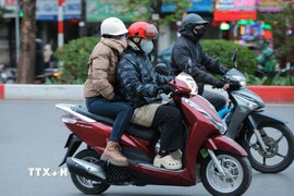 Người dân mặc áo ấm, khẩu trang, khăn quàng cổ, găng tay khi phải di chuyển ngoài trời. (Ảnh: Hoàng Hiếu/TTXVN)