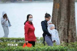 Trẻ nhỏ được che chắn kỹ chống rét khi phải di chuyển ngoài trời. (Ảnh: Hoàng Hiếu/TTXVN)