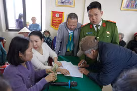 Người dân kí nhận, làm thủ tục để nhận quà của Đảng và Nhà nước. (Ảnh: Thanh Thuỷ/TTXVN)