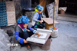 Người phụ nữ Mông tại Lùng Tám thực hiện công đoạn vẽ sáp ong lên vải lanh trước khi nhuộm chàm. (Ảnh: Lan Anh/TTXVN phát)
