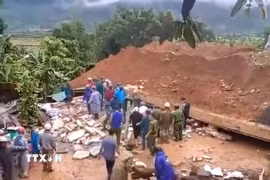 Lực lượng chức năng điều tra nguyên nhân và hỗ trợ gia đình nạn nhân. (Ảnh: TTXVN phát)
