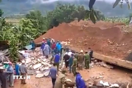 Lực lượng chức năng điều tra nguyên nhân và hỗ trợ gia đình nạn nhân. (Ảnh: TTXVN phát)